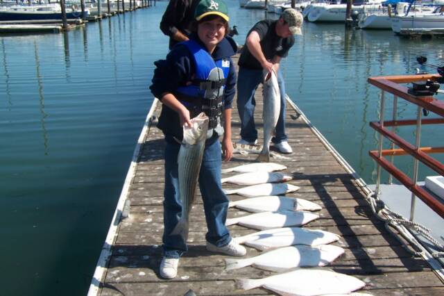 A group of people standing on a dock holding fish