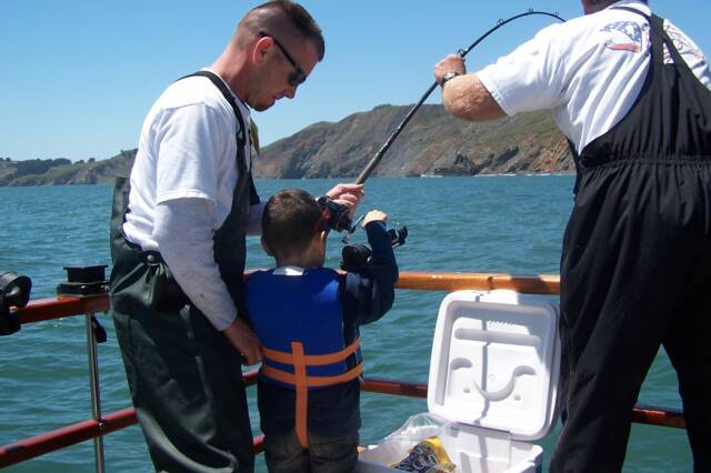 Two men and a boy are fishing on a boat