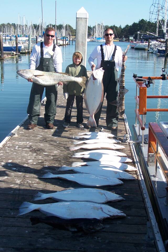 A group of people standing on a dock holding fish