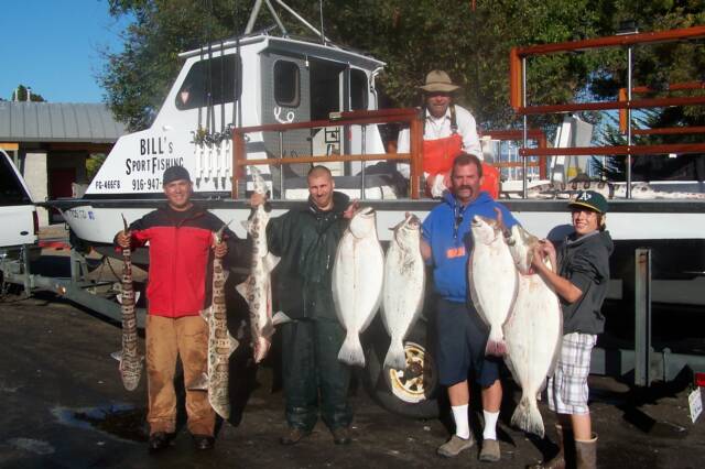 A group of men holding large fish in front of a boat that says bles