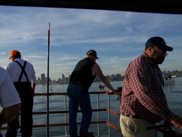 A group of men are standing on a boat looking out over the water