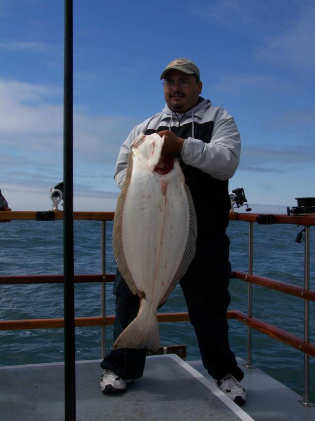 A man is holding a large fish on a boat