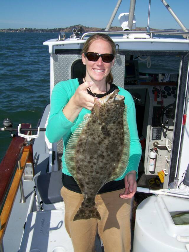 A woman is holding a large fish on a boat