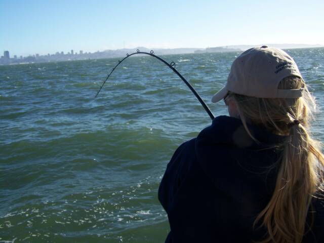 A woman in a baseball cap is fishing in the ocean