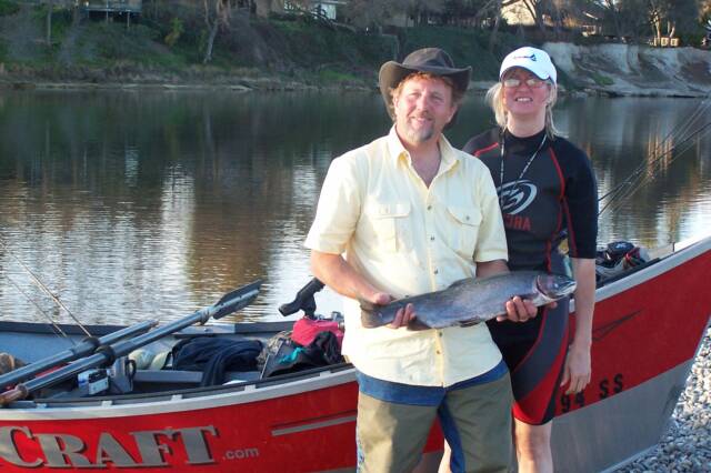 Two men holding a large fish in front of a craft boat