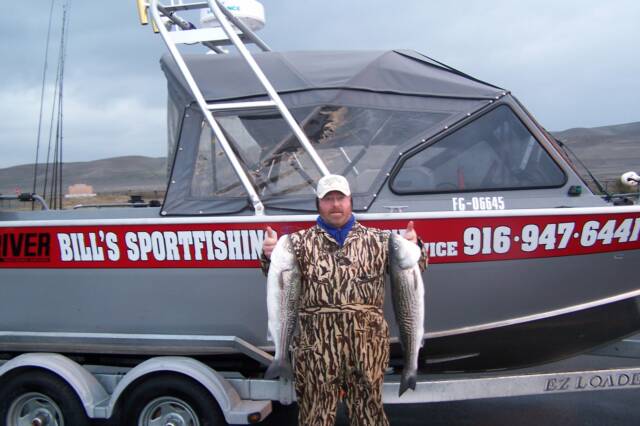 A man holding a fish in front of a boat that says river bill 's sportfishing