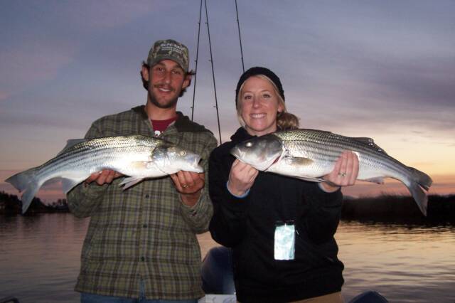 A man and a woman are holding two fish in their hands