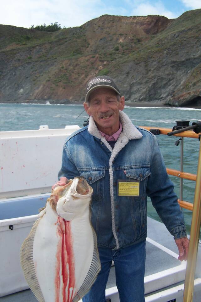 A man is holding a large fish on a boat.