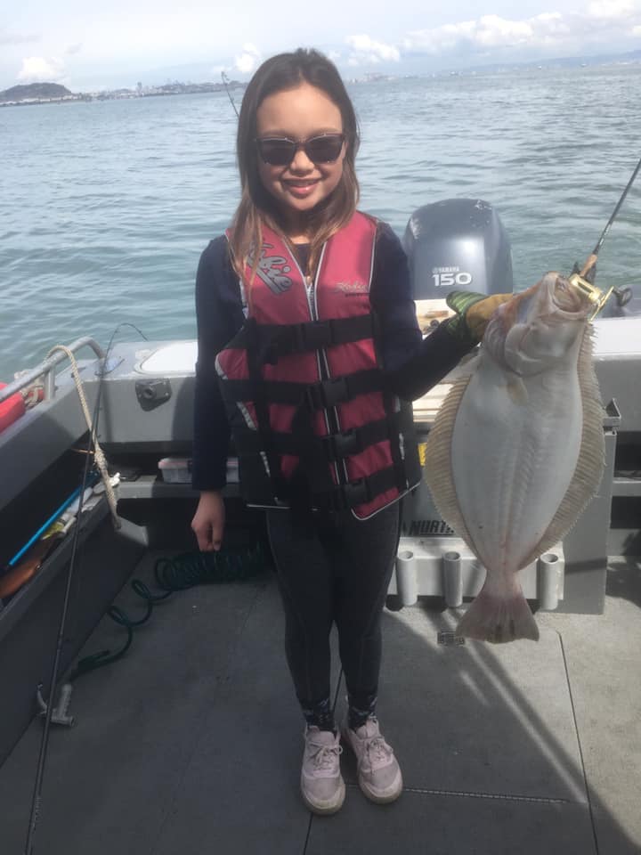 A young girl is holding a large fish on a boat.