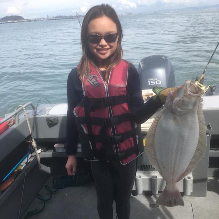 Woman holding up a Halibut fish she caught on San Francisco Bay. 