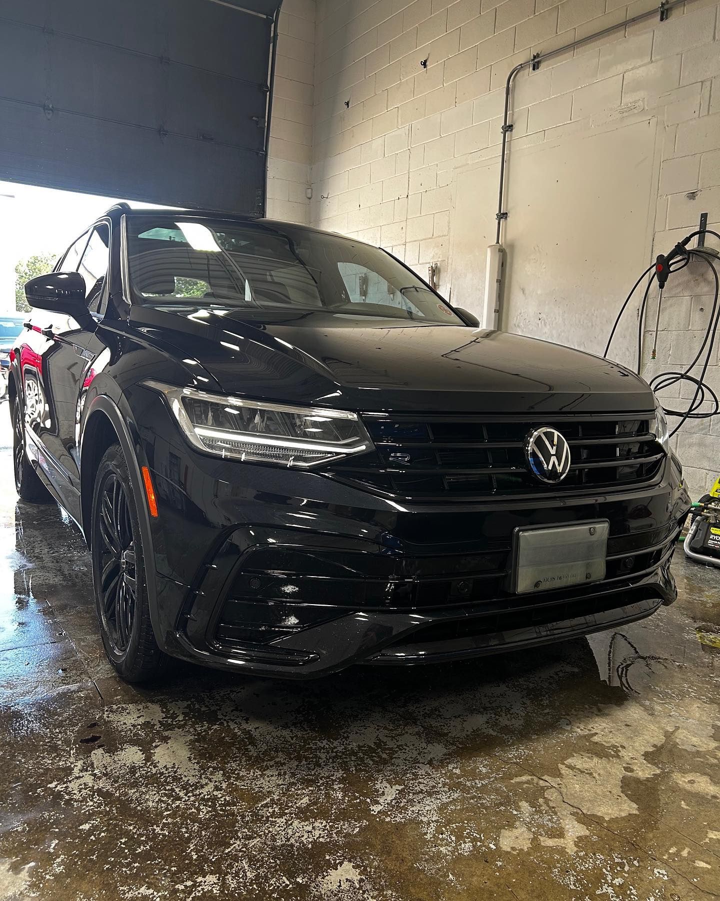 A black volkswagen tiguan is sitting in a garage.