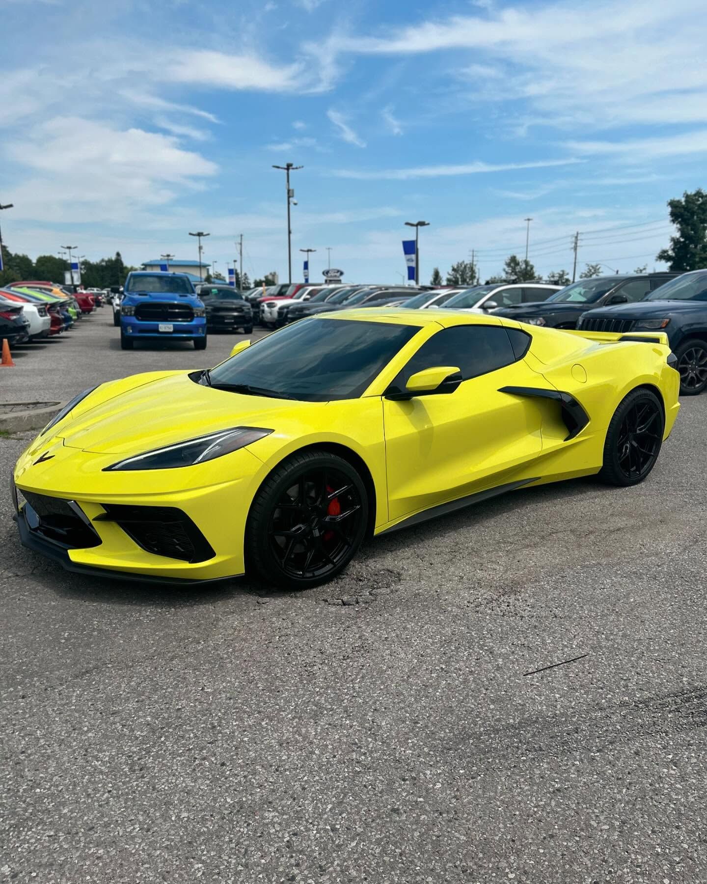 A yellow corvette is parked in a parking lot.