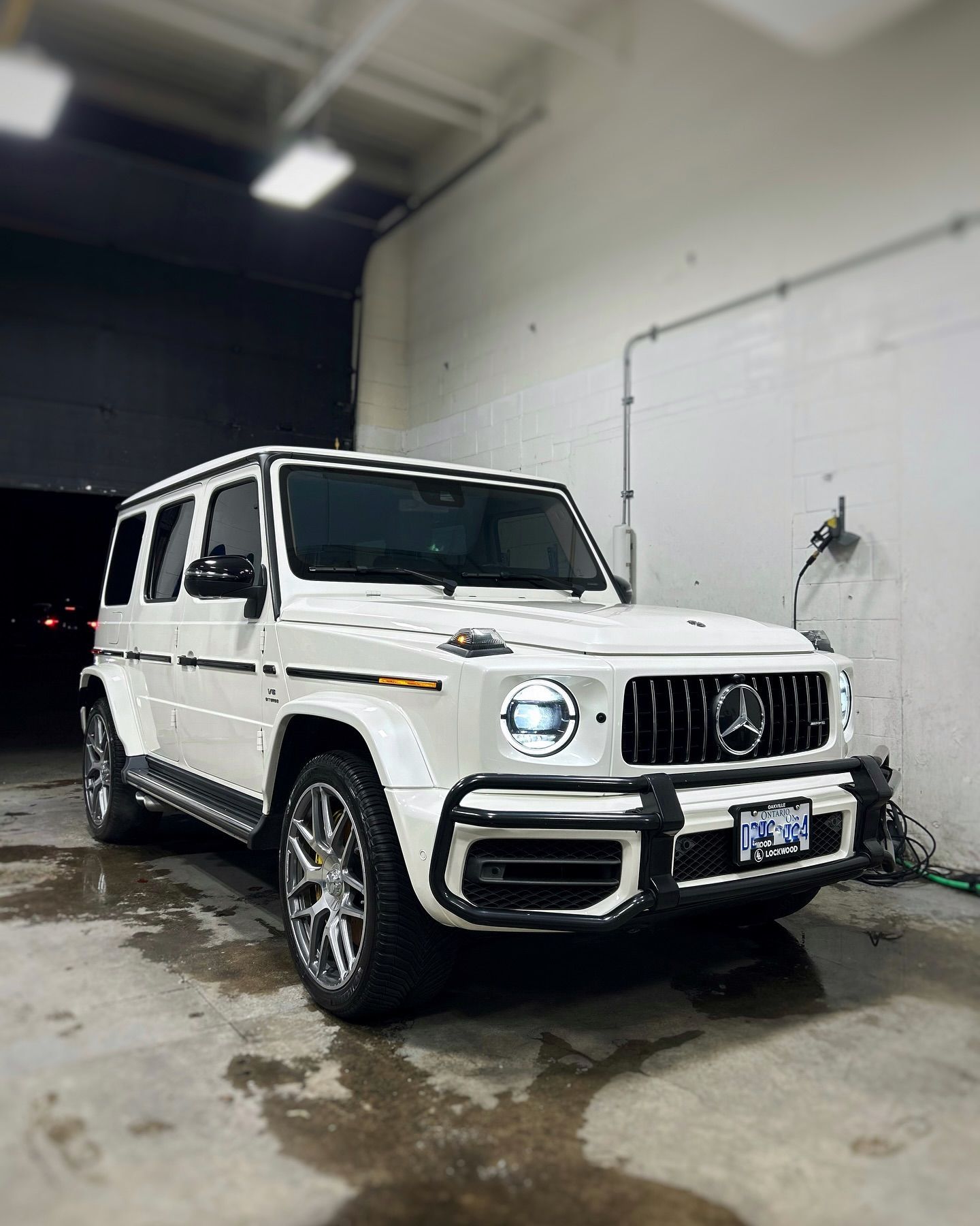 A white mercedes benz g63 amg is parked in a garage.