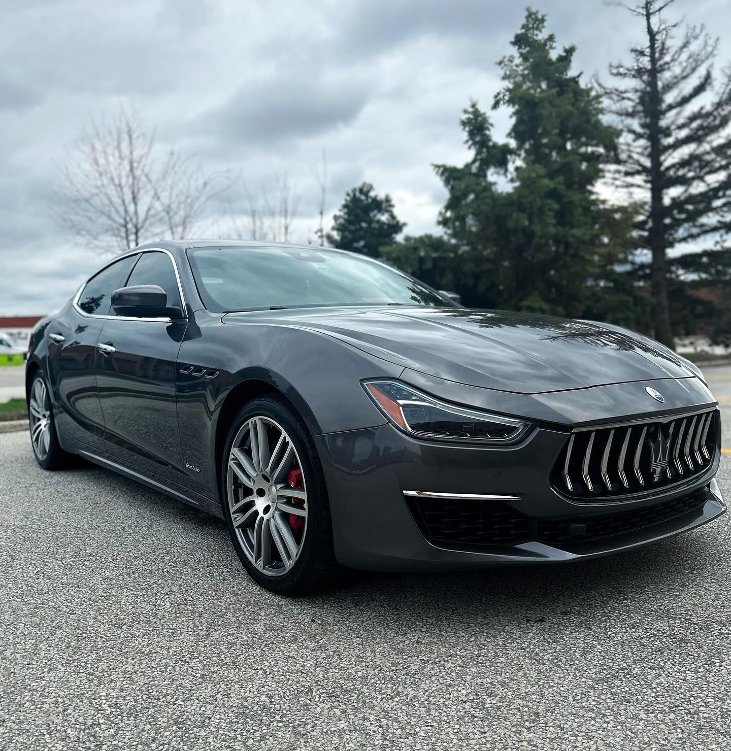 A gray maserati ghibli is parked on the side of the road.