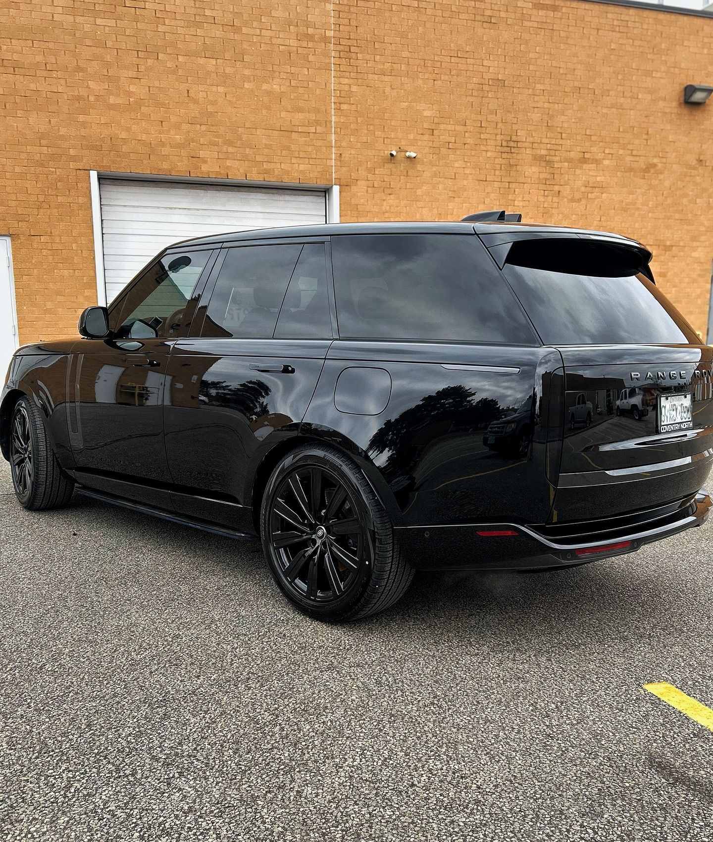 A black range rover is parked in front of a brick building.