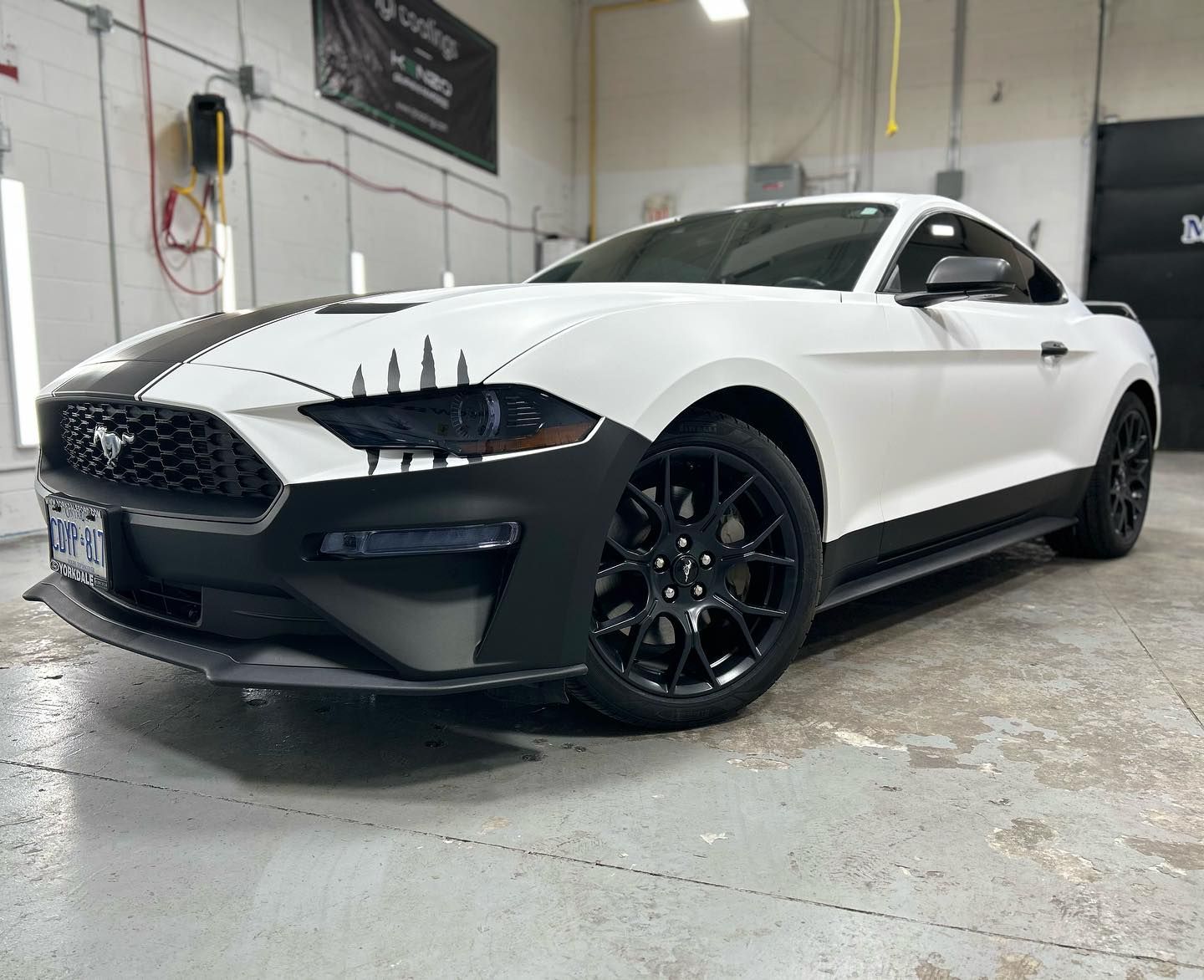 A white ford mustang is parked in a garage.