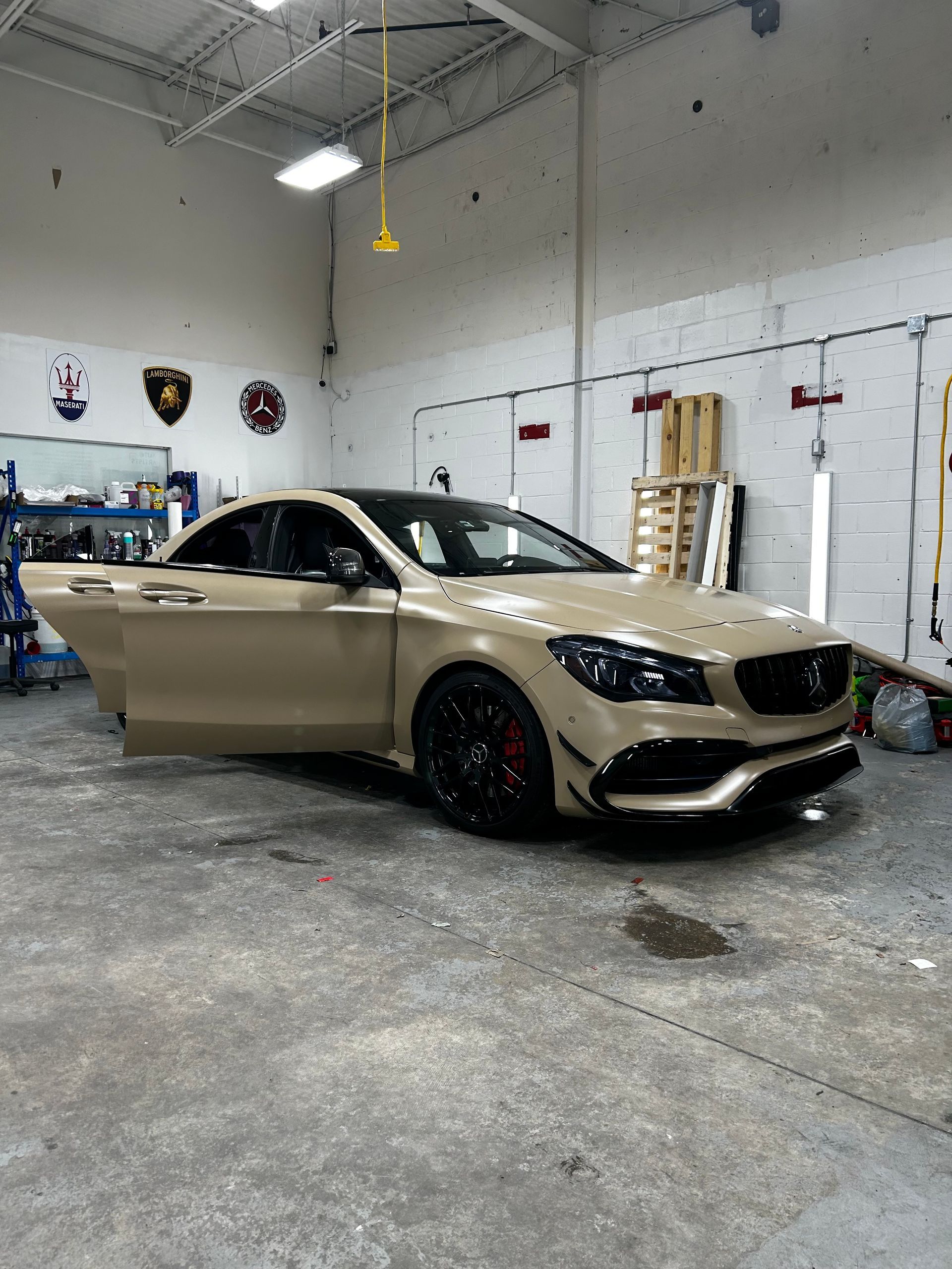 A car is parked in a garage with its doors open.