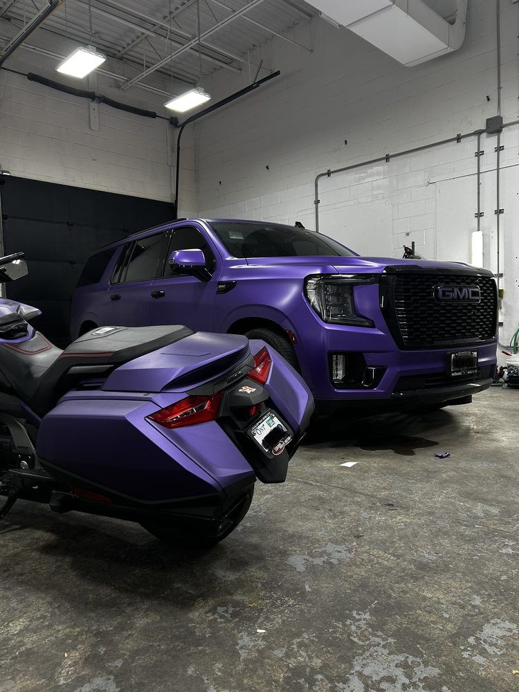 A purple suv and a purple motorcycle are parked in a garage.