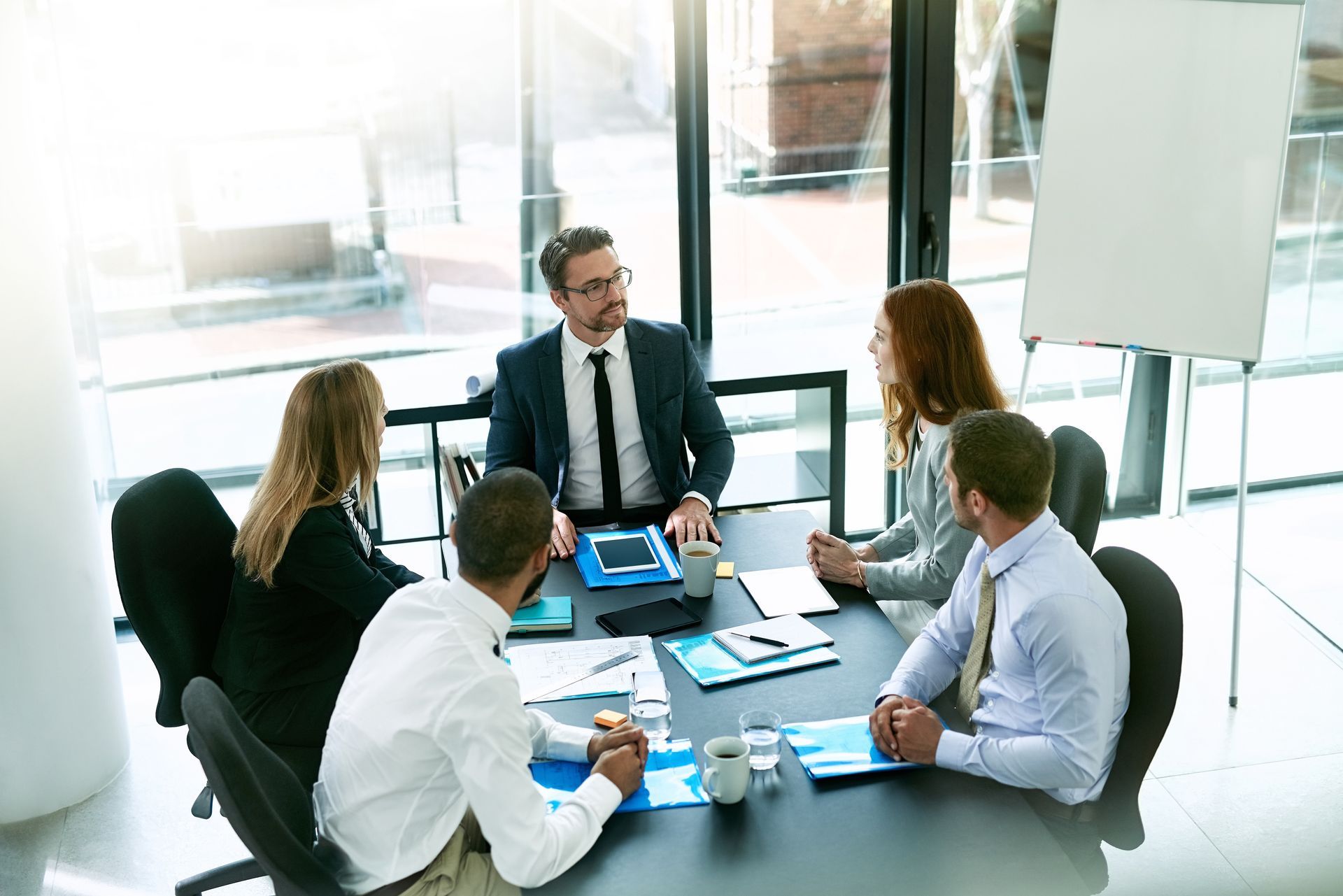 A group of business people are sitting around a table having a meeting.