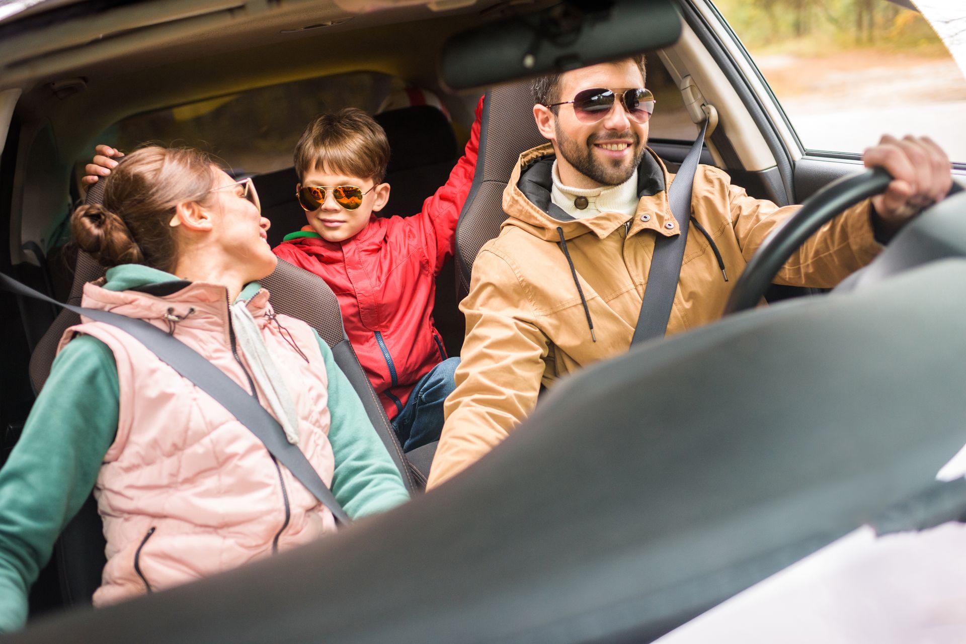 A family is sitting in the back seat of a car.
