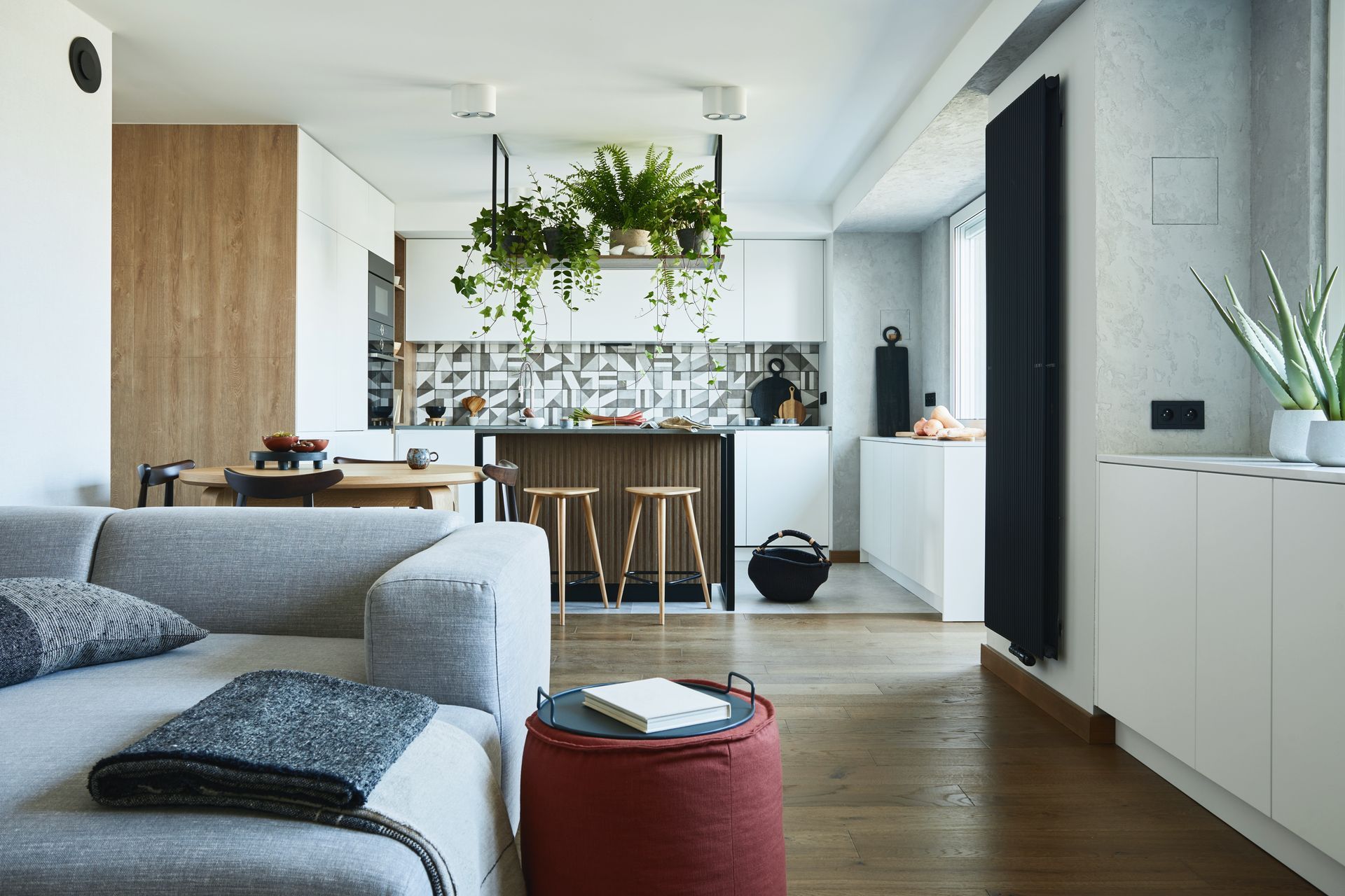 A living room with a couch , ottoman , table and plants.
