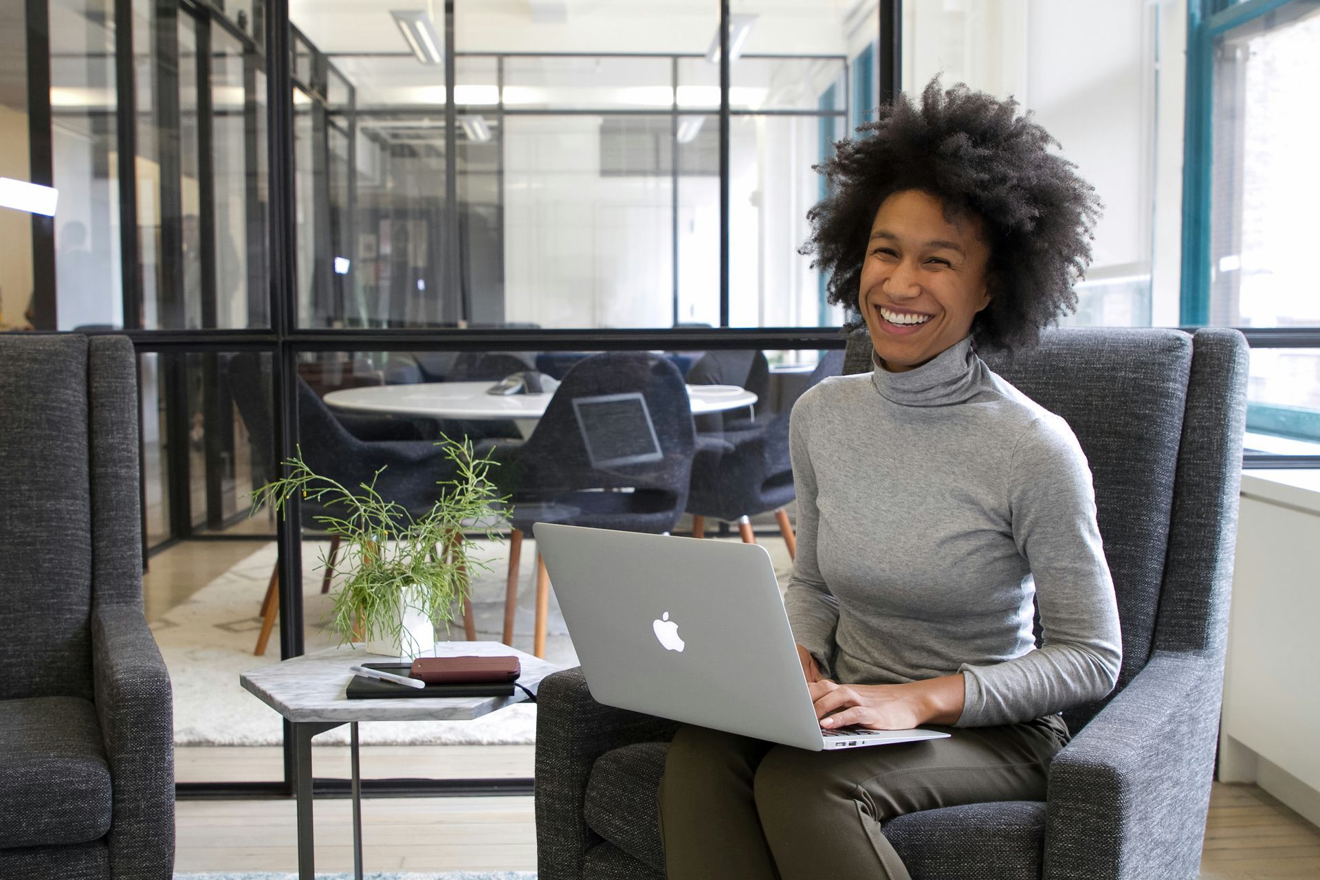 A woman is sitting in a chair using a laptop computer.