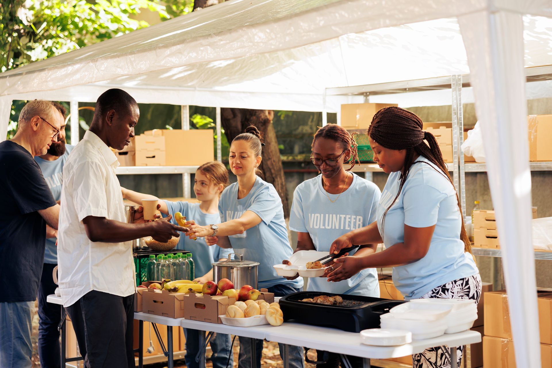 A group of people are standing around a table serving food.
