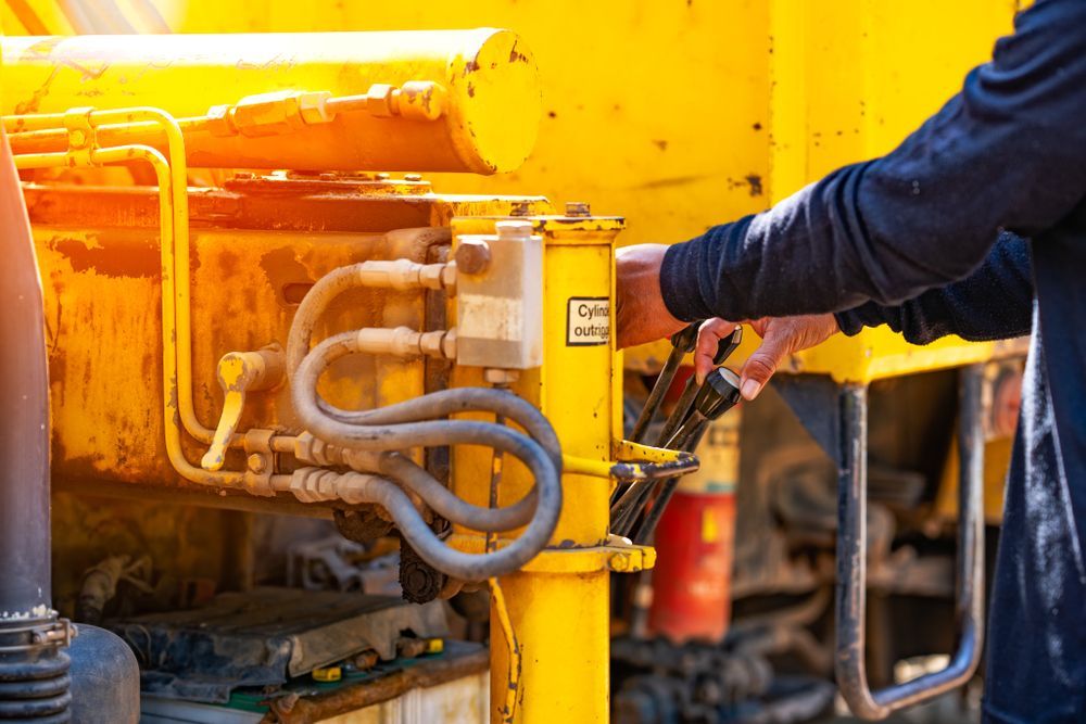 A Man is Working on a Yellow Construction Vehicle — Hydrofit Service in Wollongong, NSW