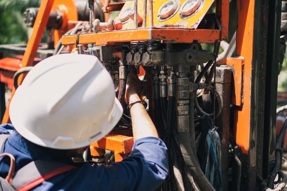 A Man Wearing a Hard Hat is Working on a Machine — Hydrofit Service in Wollongong, NSW