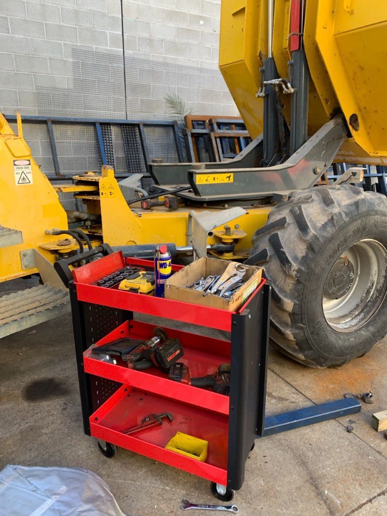 A Red Tool Cart is Sitting Next to a Yellow Dump Truck — Hydrofit Service in Wollongong, NSW