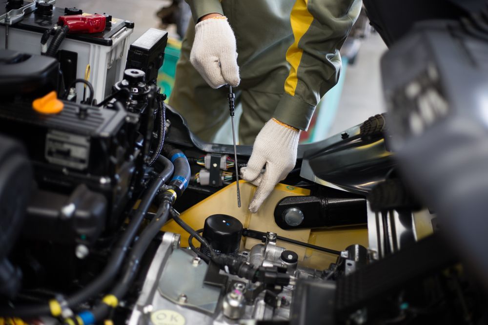 A Man is Working on a Car Engine With a Screwdriver — Hydrofit Service in Wollongong, NSW