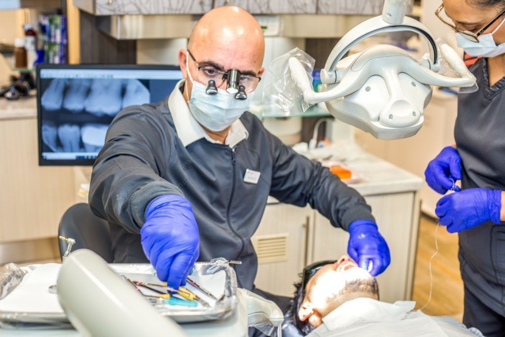 A dentist is examining a patient 's teeth in a dental office.