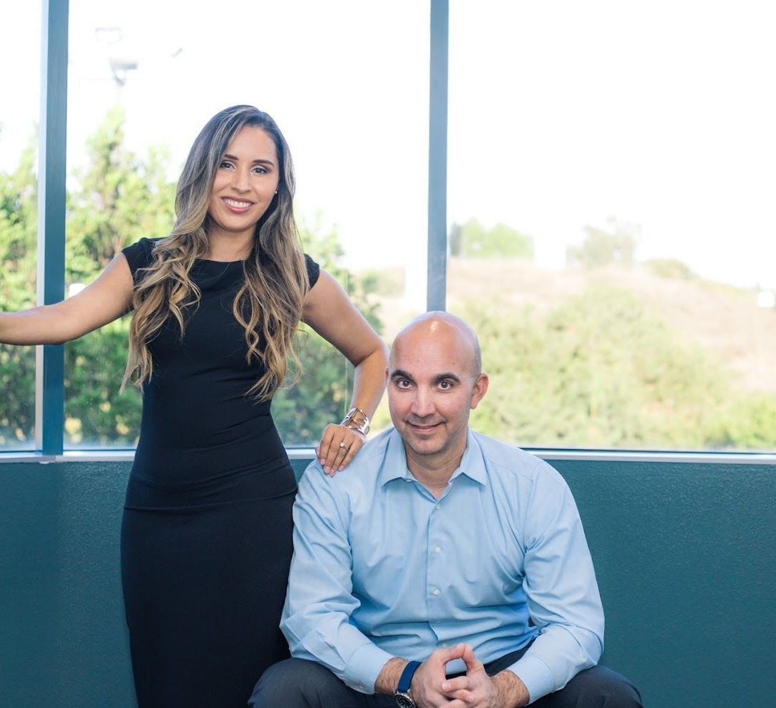 A man and a woman are posing for a picture in front of a window.