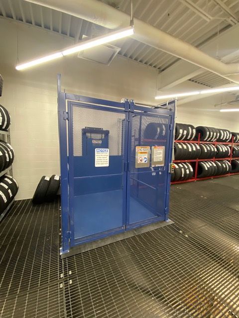 An elevator with a glass door and stairs in the background.