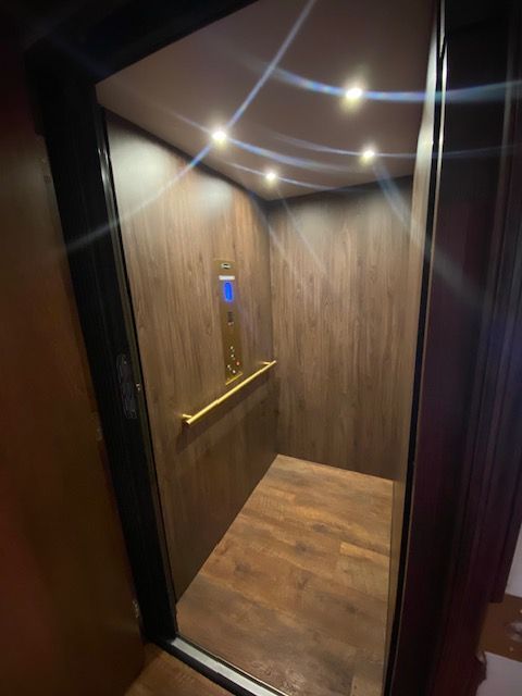 A white elevator is in the middle of a hallway next to a staircase.