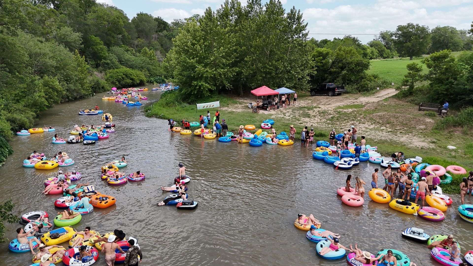A large group of people are floating down a river in rafts.