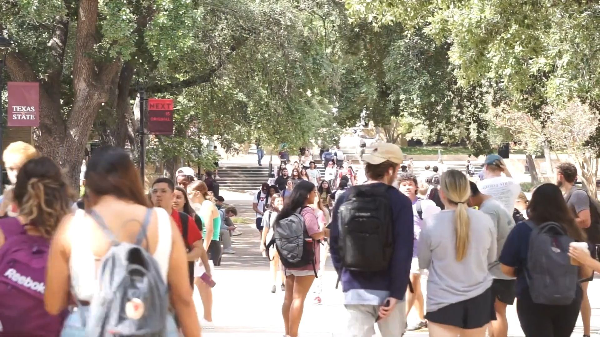 A large group of people are walking down a sidewalk.