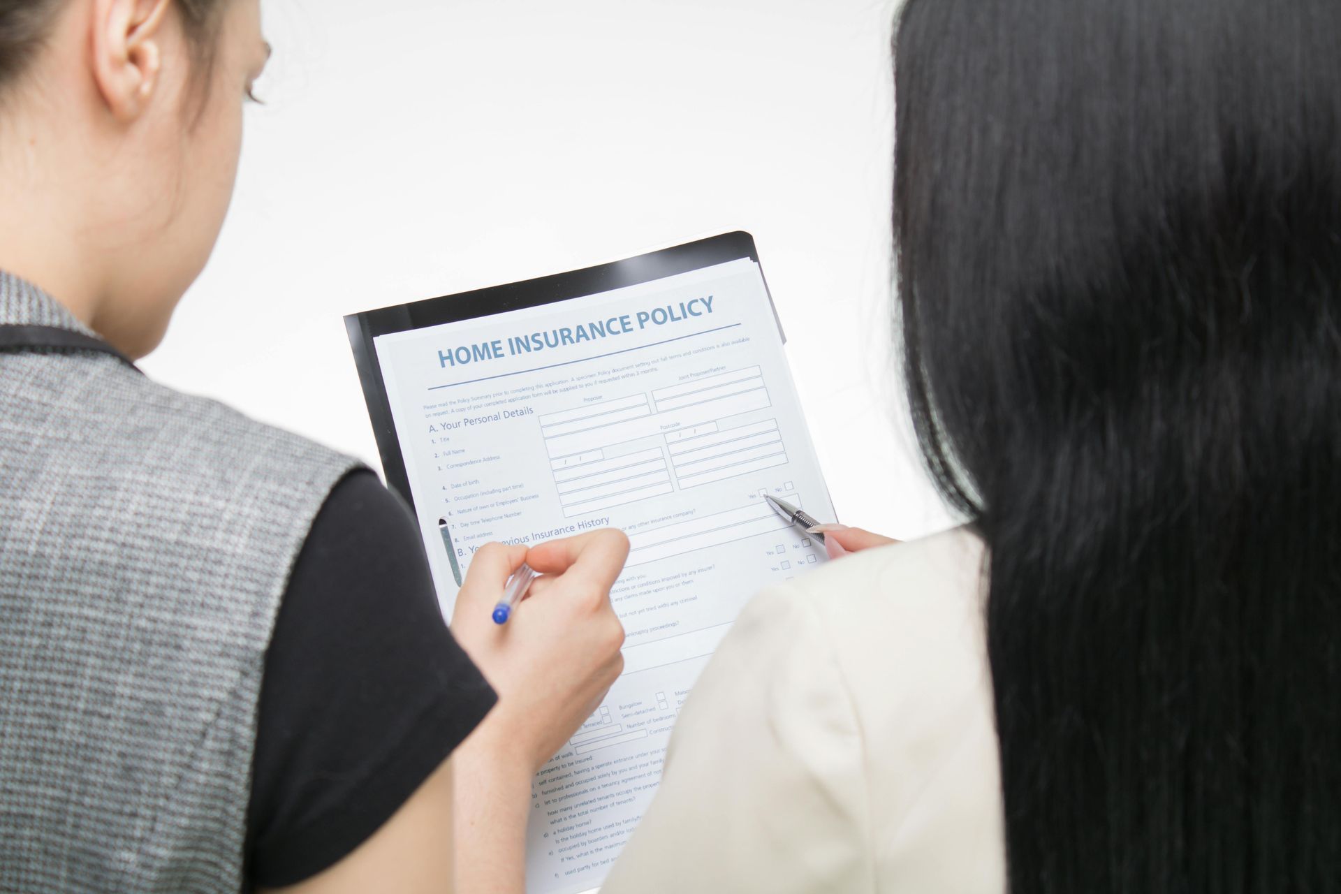 Two people reviewing document, one person pointing pen, the other with long black hair, white background.