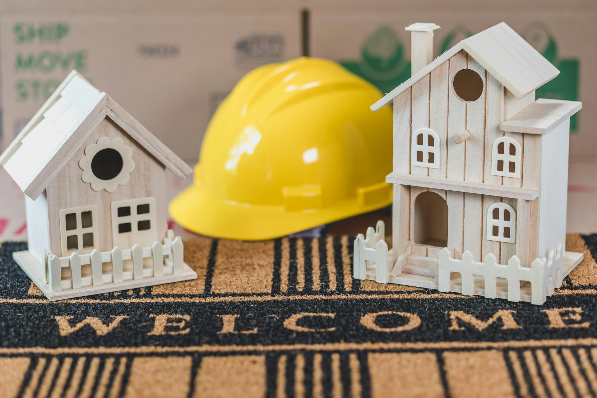 A welcome mat with miniature houses and a hard hat on it
