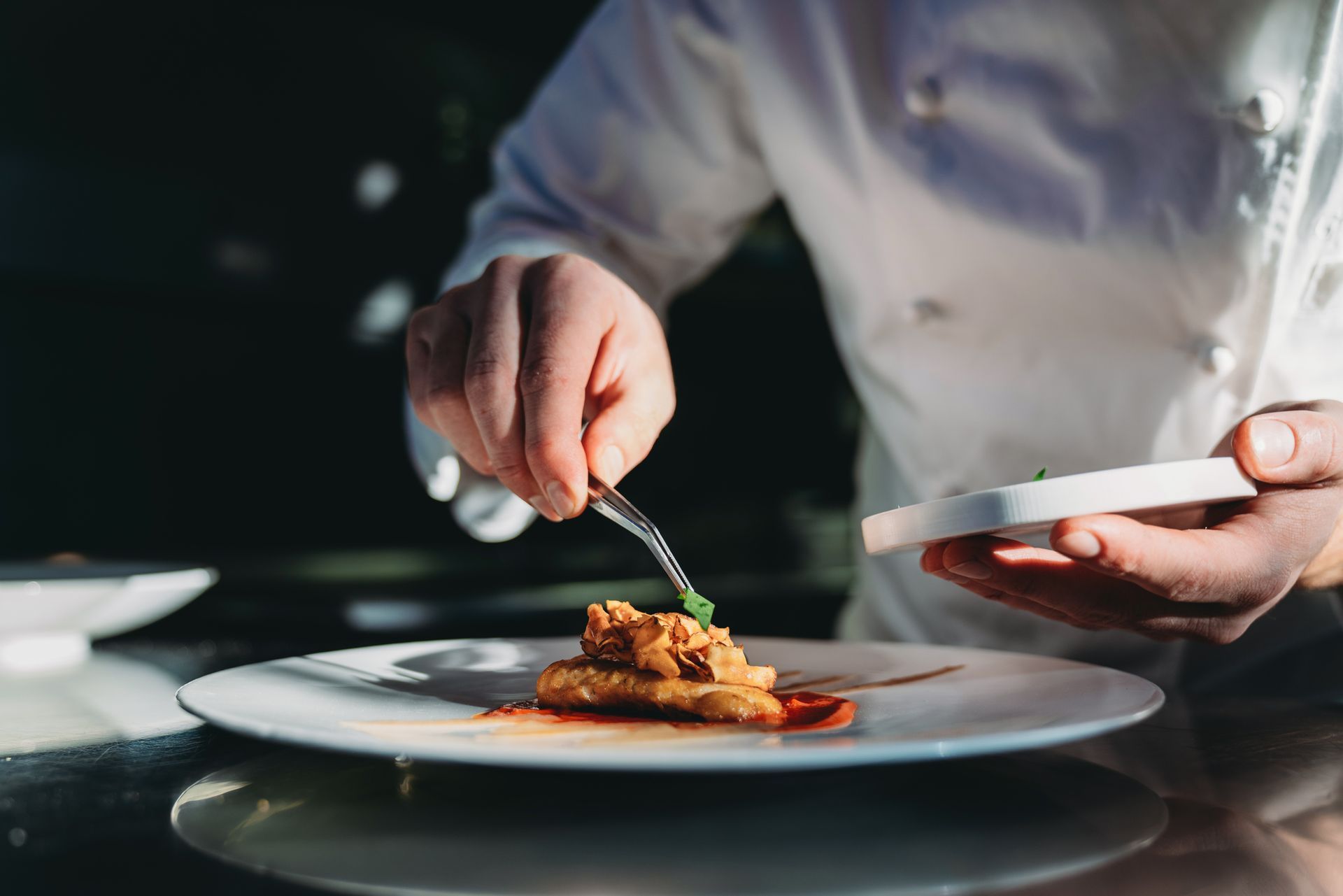 Uno chef sta decorando un piatto di cibo con una forchetta.