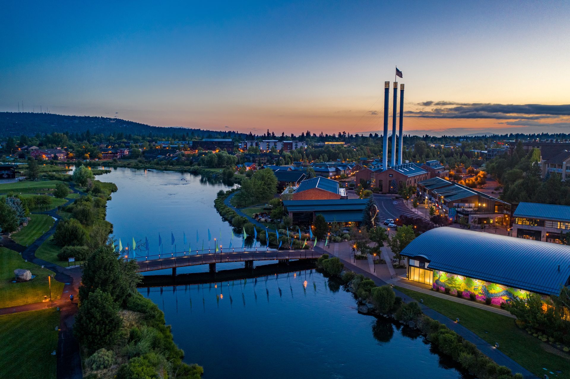 an aerial view of a city with a bridge over a river at sunset .