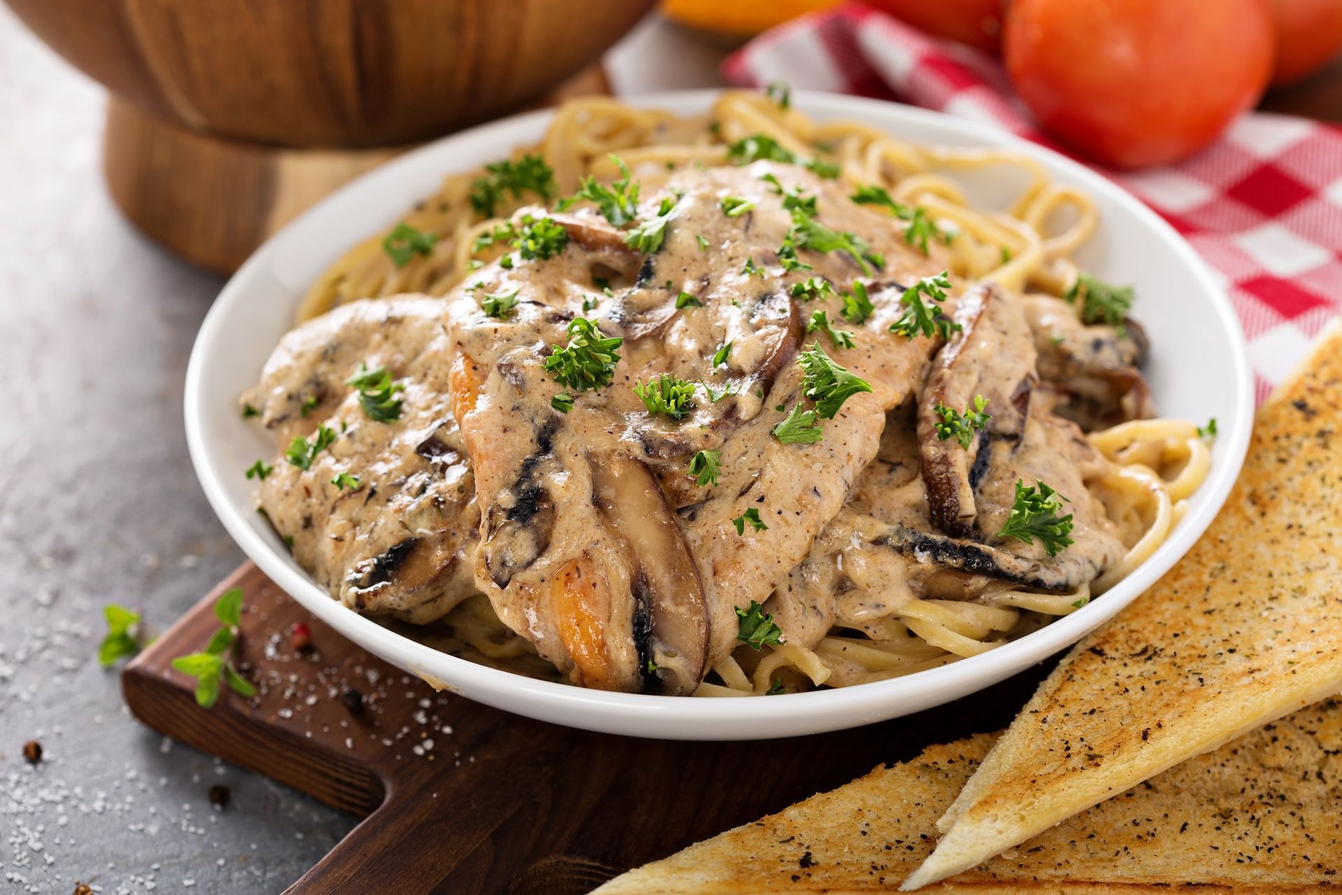 a bowl of pasta with chicken and mushrooms on a table .