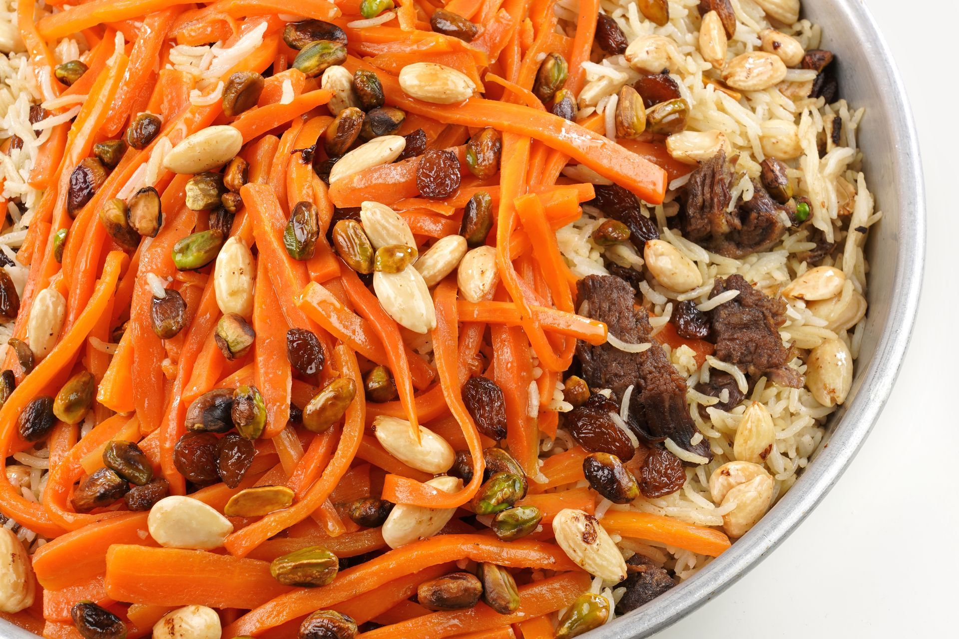 a bowl of carrots , rice , raisins and pistachios .