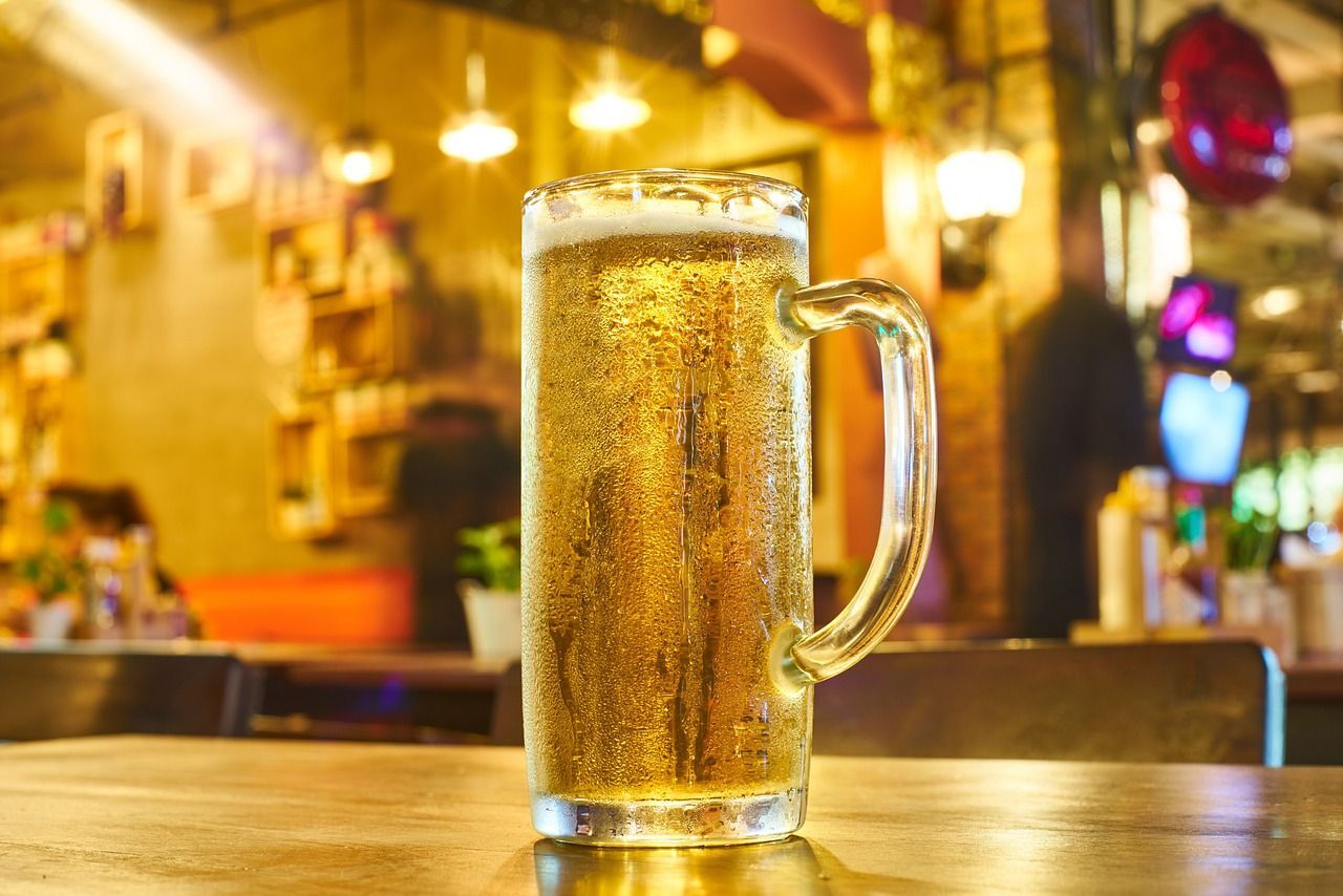 a glass of beer is sitting on a wooden table in a restaurant .