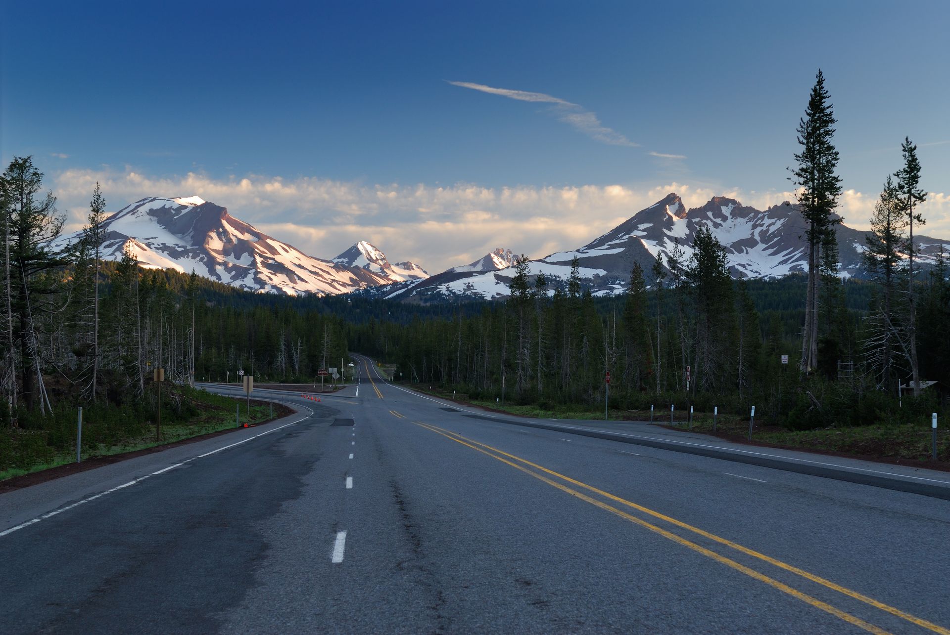 an empty highway with snowy mountains in the background