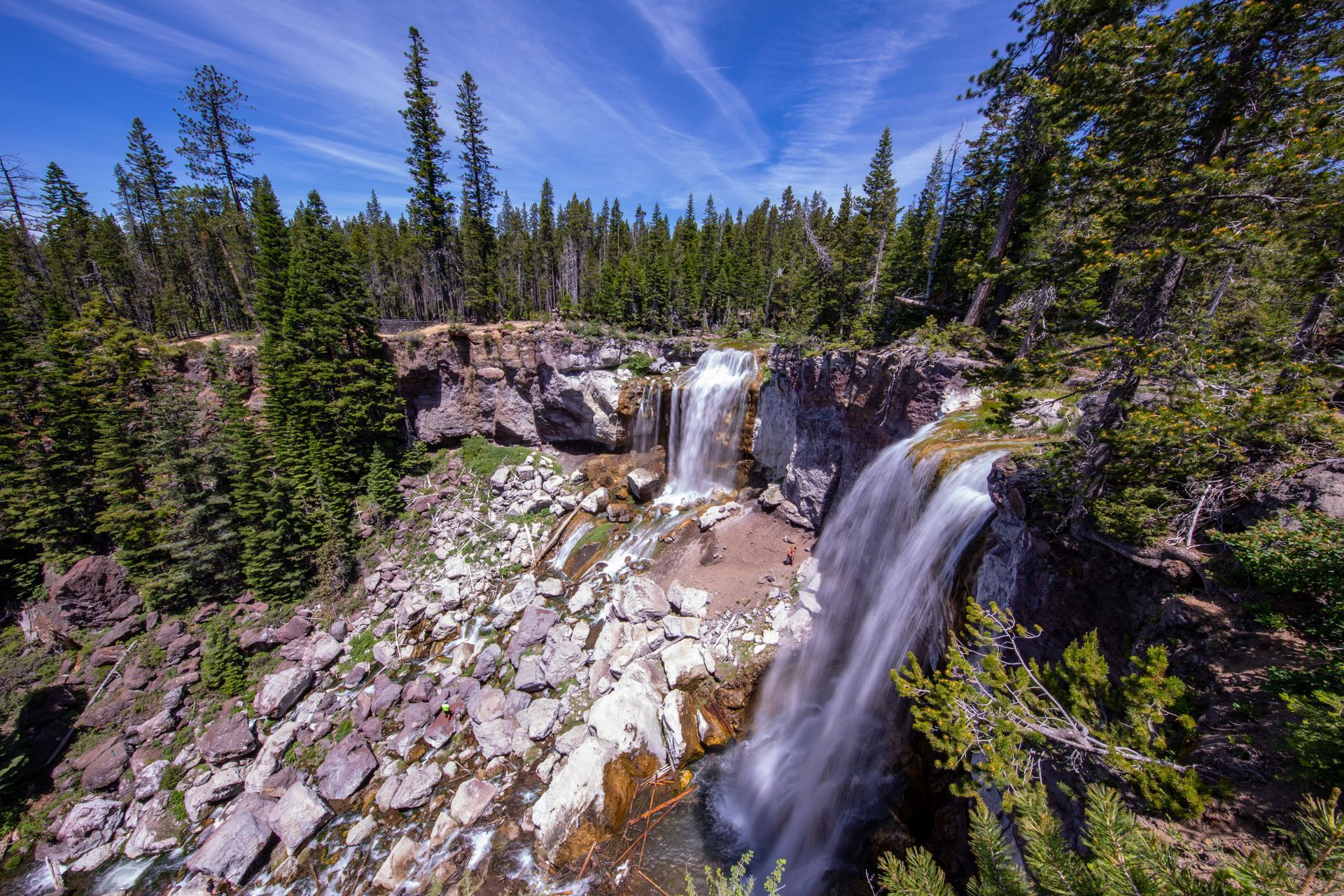 a waterfall is surrounded by trees and rocks in the middle of a forest .
