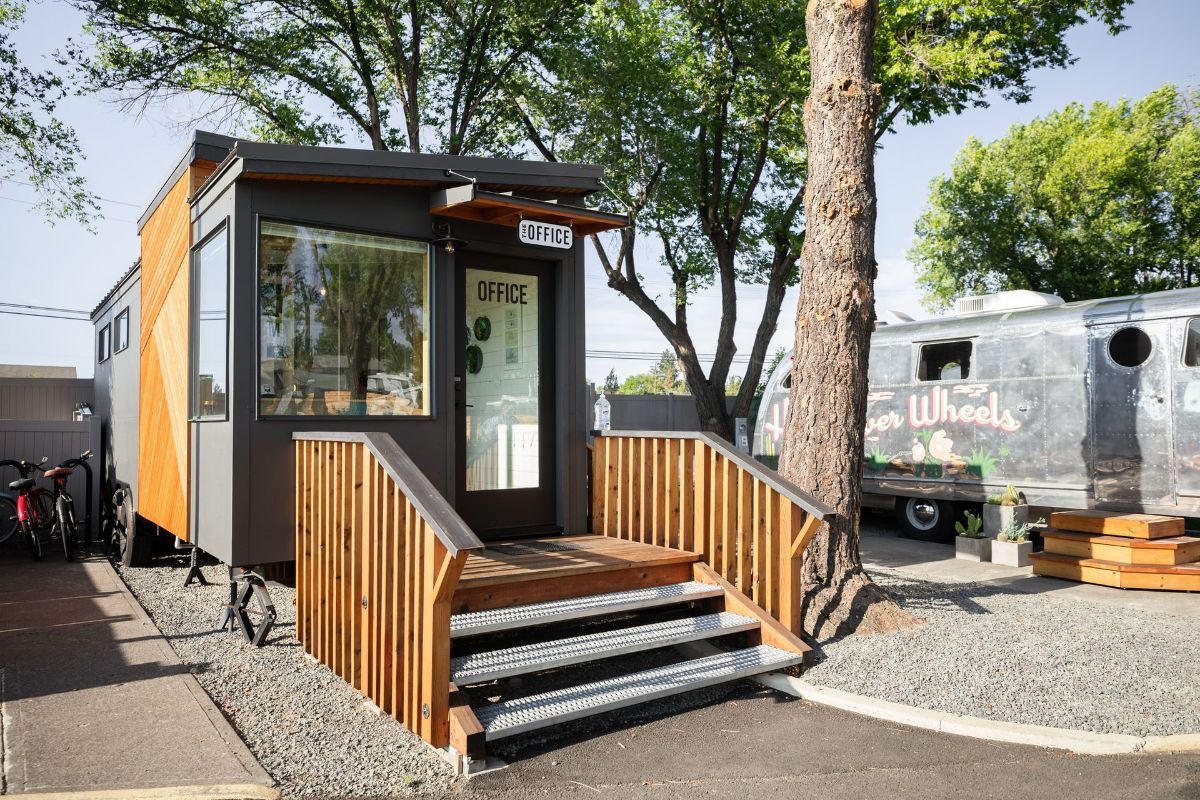 a small building with stairs leading up to it is sitting next to a trailer .