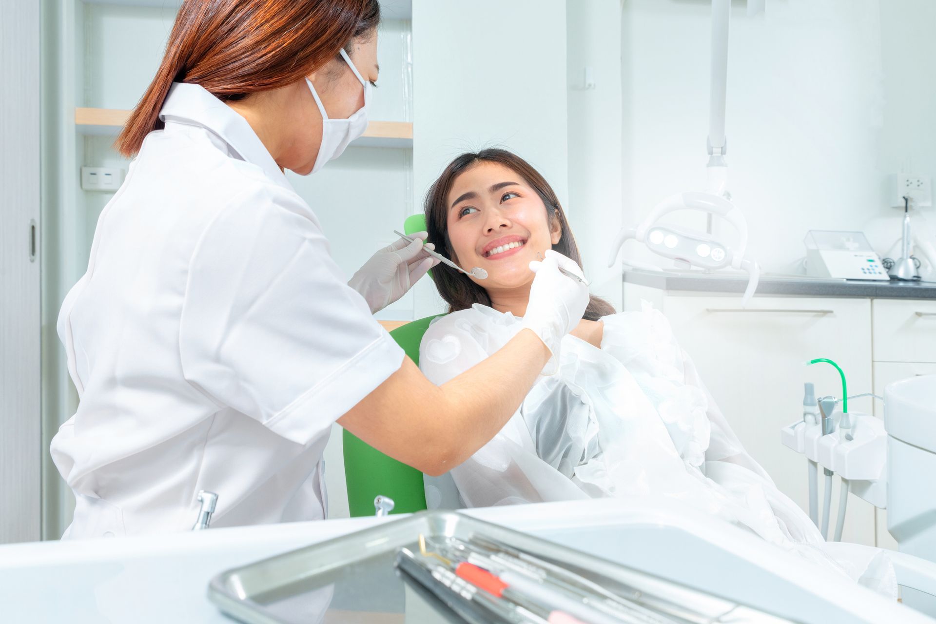 A dentist is examining a woman patient's teeth during a dental check-up at the dentist's clinic.