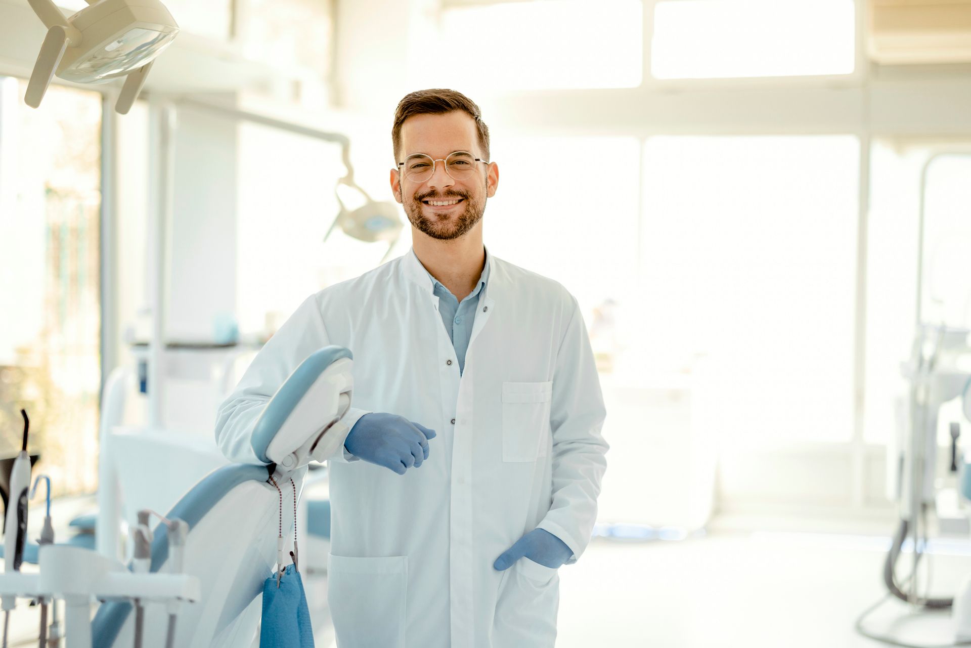 Smiling young dentist in a dental clinic, wearing scrubs and providing care to patients.