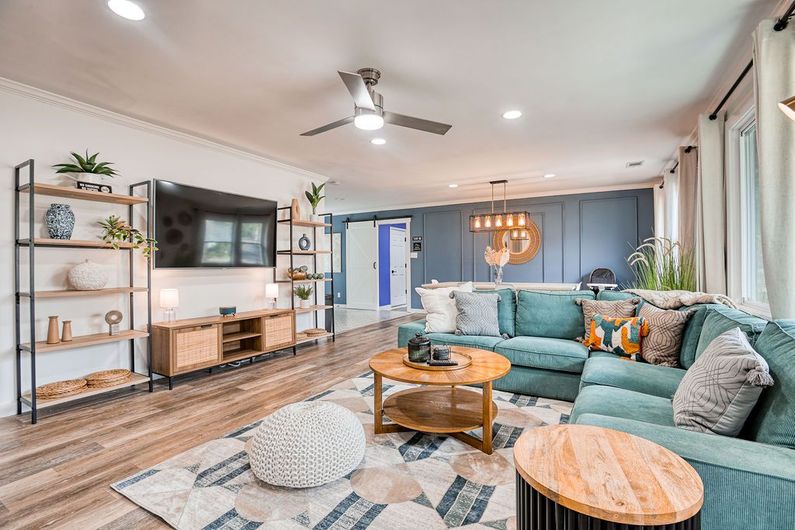 Living room with teal sectional, wood coffee tables, and built-in shelving.